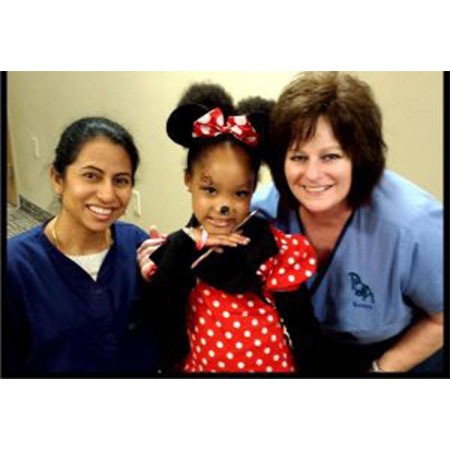 Pediatric Dental Associates employees posing with a young girl